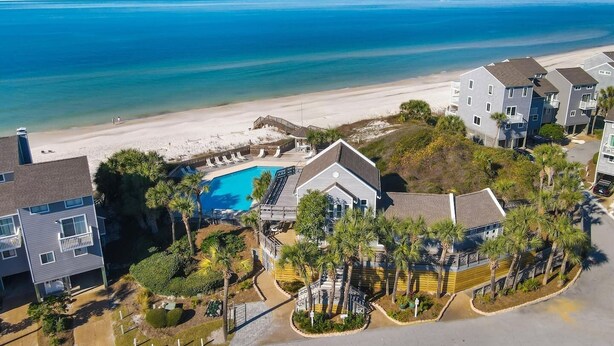 A coastal residential area with a swimming pool, beachfront, and multi-story buildings.