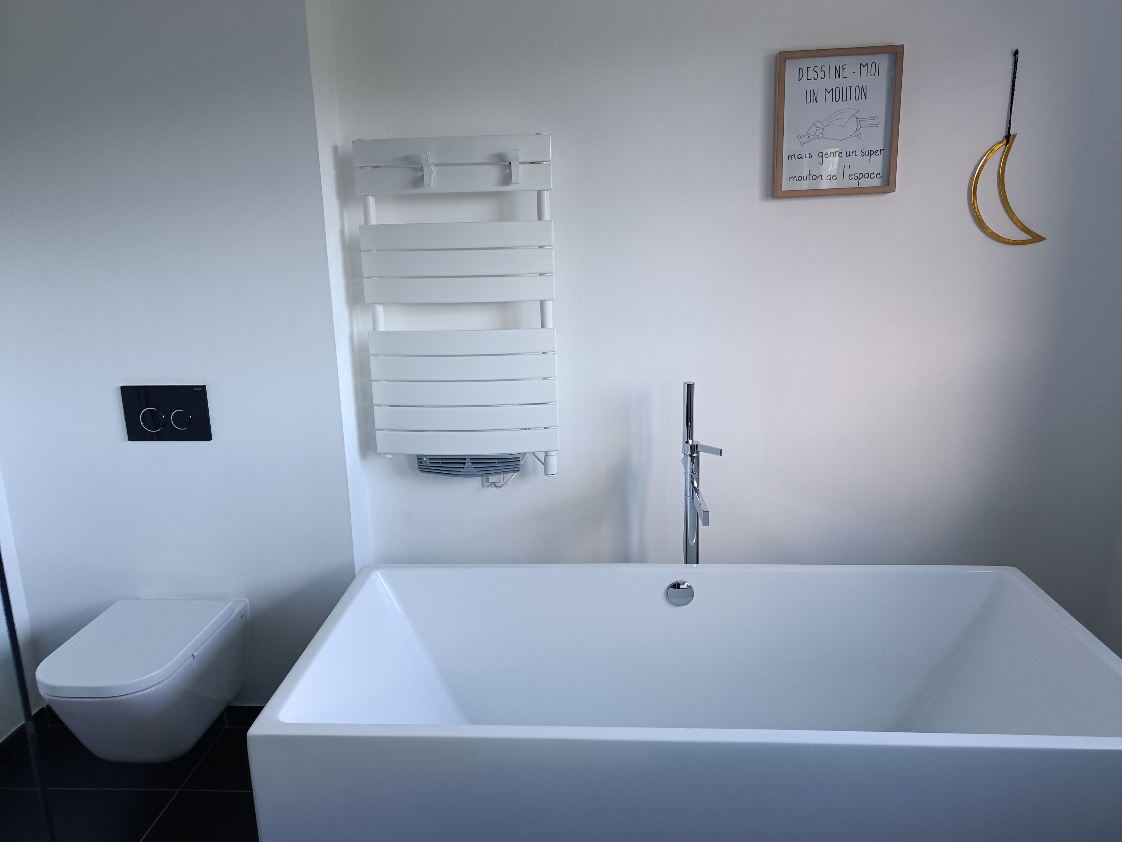 Une salle de bain moderne avec une baignoire blanche, des toilettes et un porte-serviettes.
