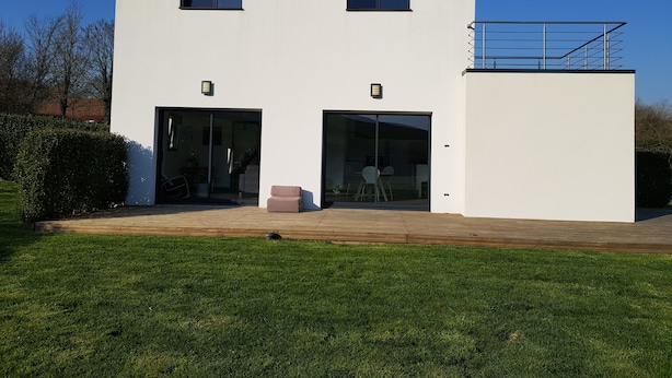 Un edificio moderno de dos pisos con grandes puertas de cristal y un pequeño balcón en el piso superior.