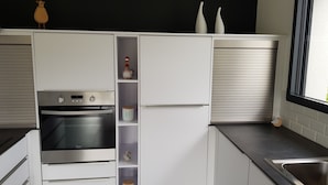 Una cocina moderna con electrodomésticos integrados, una ventana y una pared negra.