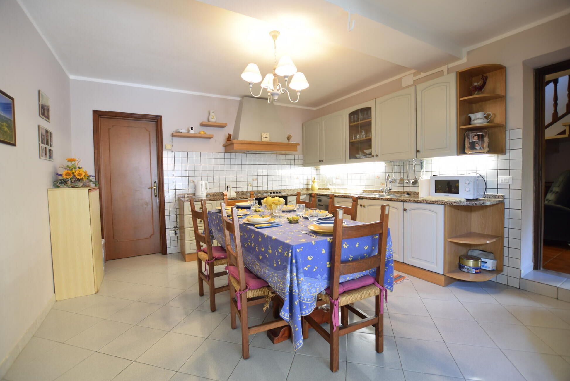 A kitchen with a dining table set for four, a microwave, and a cabinet with shelves.