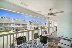 A balcony with a table, chairs, and a ceiling fan.