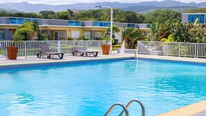 Una piscina con sillas de descanso y una valla blanca.
