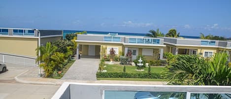 A row of modern buildings with a clear view of the ocean, a paved driveway, and well-maintained landscaping.