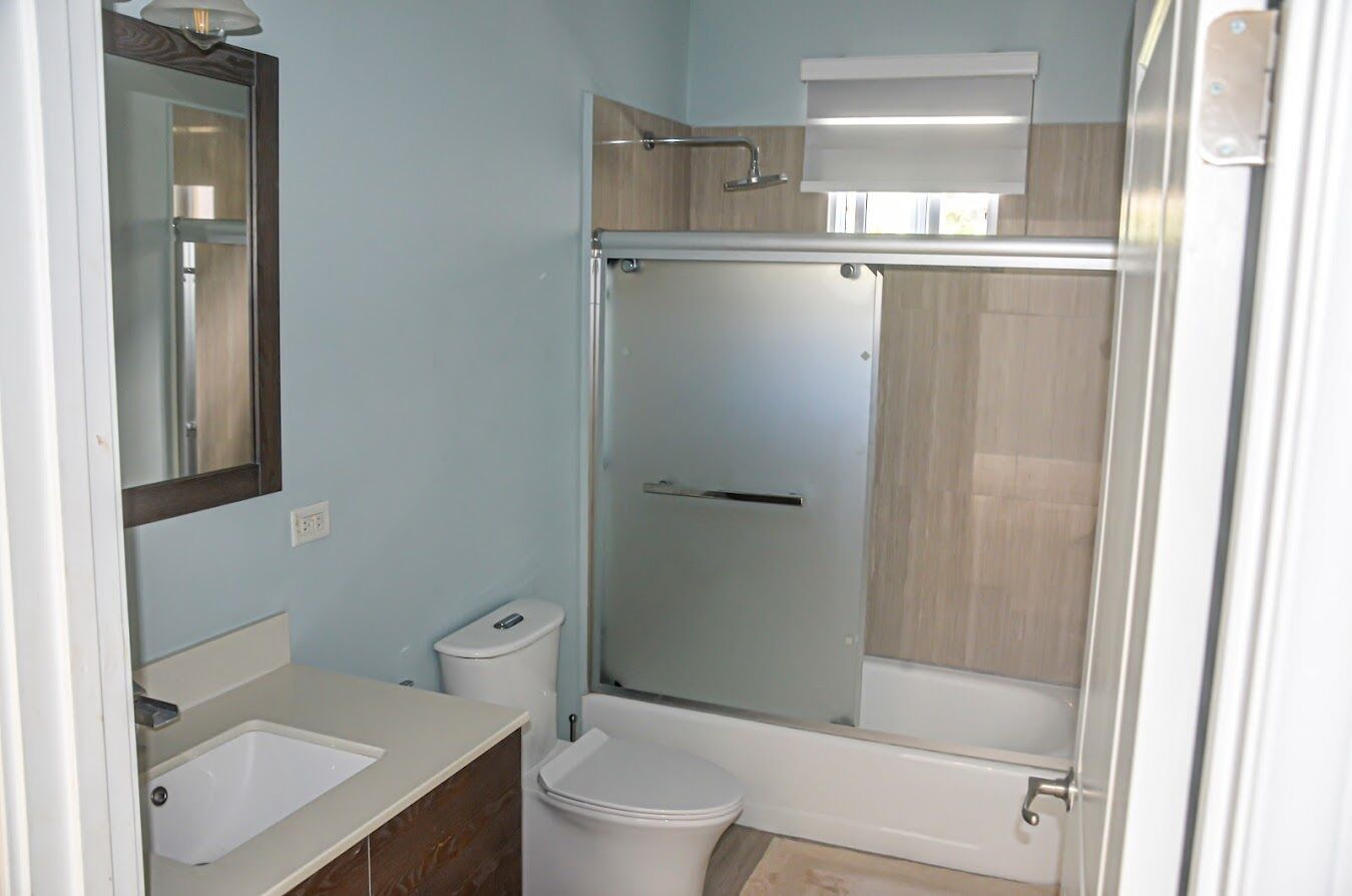 A bathroom with a glass-enclosed shower, a white toilet, and a sink.