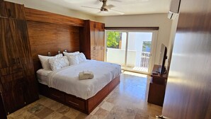 A bedroom with a large bed, wooden wardrobe, and a balcony with a view.