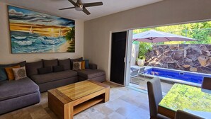 A living room with a gray sofa, a wooden coffee table, and a painting of a sunset over the ocean.
