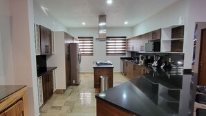 A modern kitchen with wooden cabinets, a central island, and a built-in oven.