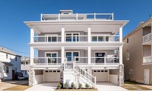 Un immeuble résidentiel de deux étages doté d’un escalier central, de balcons et d’un garage.
