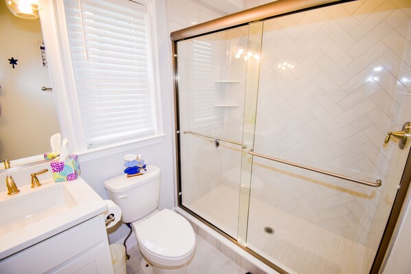 Une salle de bain avec une douche à parois de verre, des toilettes blanches et un lavabo avec un miroir.