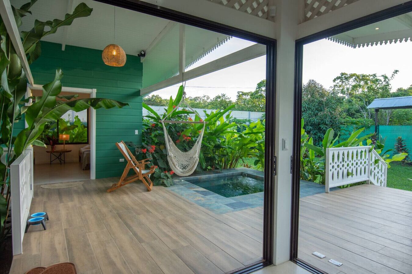 Un patio esterno moderno con un pavimento in legno, un'amaca e una piccola piscina.