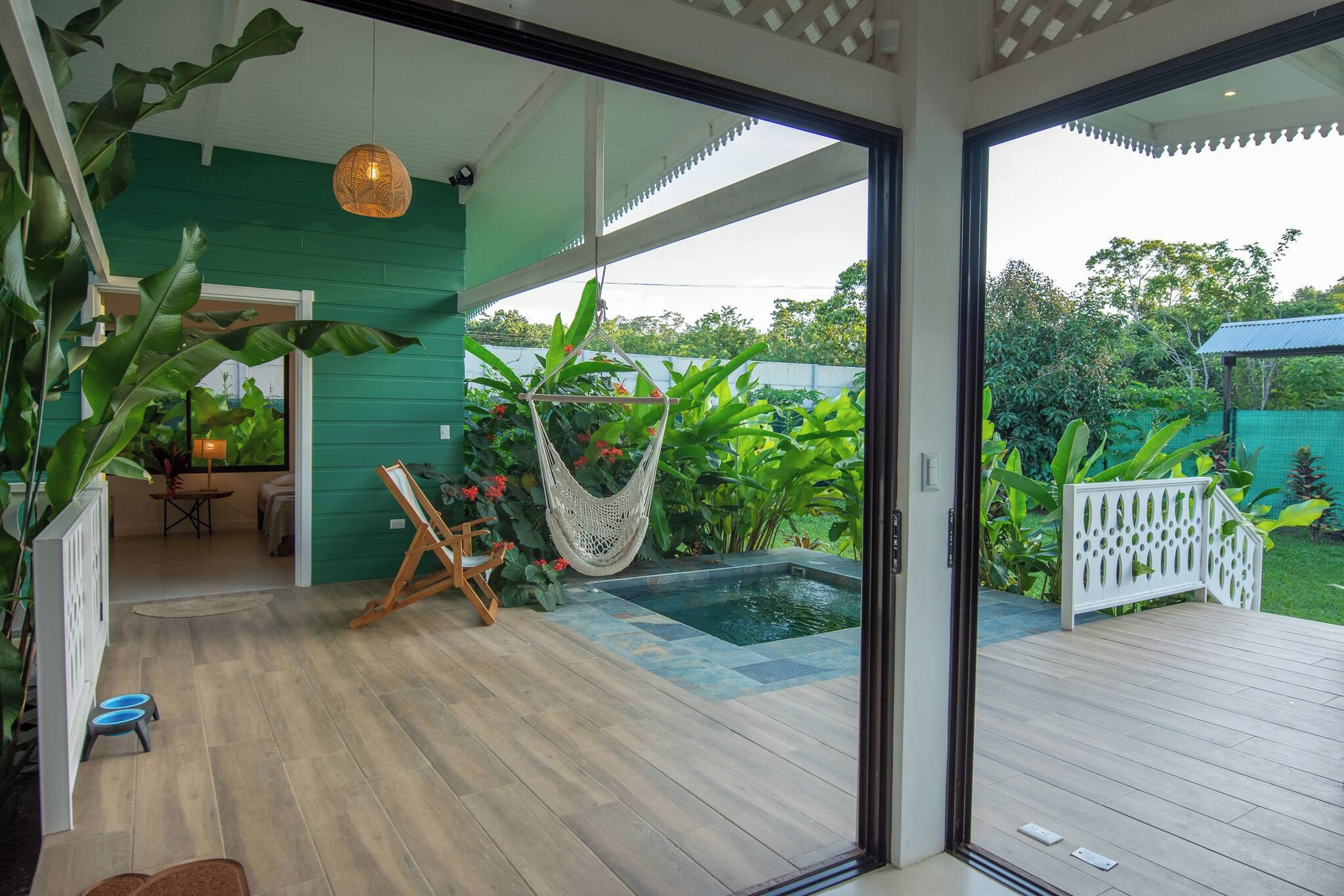 A modern house with a wooden deck, a hammock, and a pool.