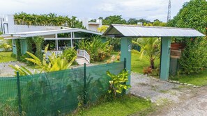 Il s’agit d’une propriété résidentielle dotée d’une cour clôturée, d’un porche abrité et d’un petit bâtiment dont le toit est fait de tôle ondulée.