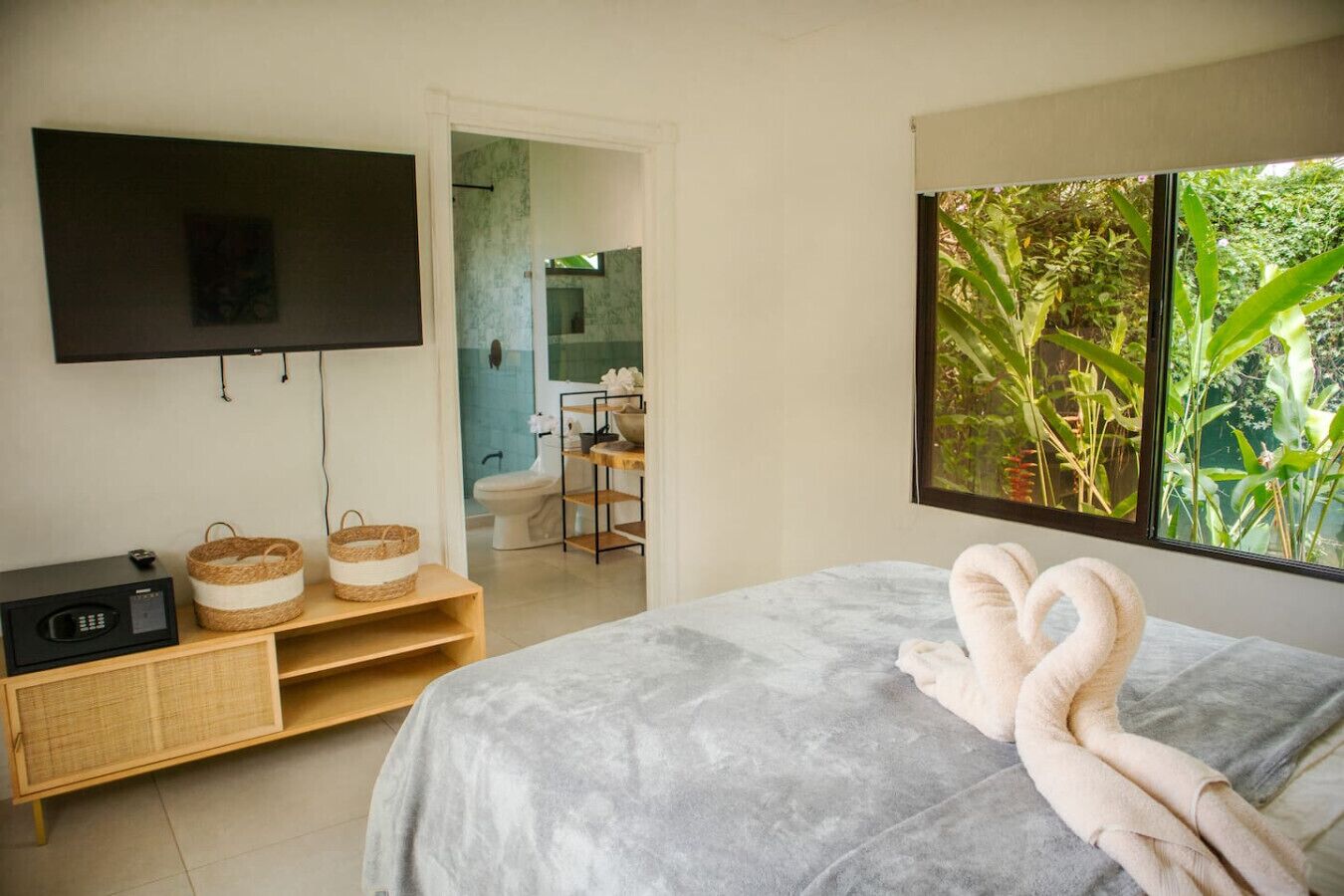 Una camera da letto con un letto, una TV, un armadietto in legno e una finestra vista verde.