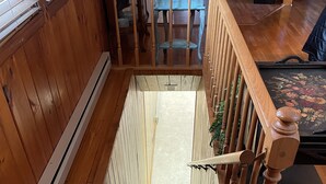 A wooden staircase with a handrail, carpeted steps, and a view of a dining area with a table and chairs. - Cozy Mtn. Home in Newland (Newland)