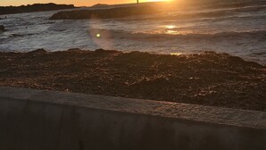 A sunset over a beach with waves, a concrete barrier, and a distant shoreline. - T4 100m2 beach 250m Six fours (Six-Fours-les-Plages)