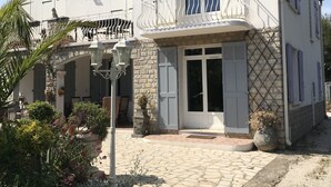 A two-story house with a balcony, stone facade, and a garden area with various plants and flowers. - T4 100m2 beach 250m Six fours (Six-Fours-les-Plages)