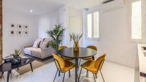 Ein modernes Wohnzimmer mit einem runden Esstisch, gelben Stühlen, einer Couch und einem Couchtisch.