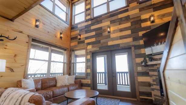 A cozy cabin interior with a brown leather sofa, a round table, and a fireplace.