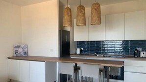 A modern kitchen with white cabinets, a wooden countertop, and three wicker pendant lights. - Simius beach - [Free Parking] (Simius)