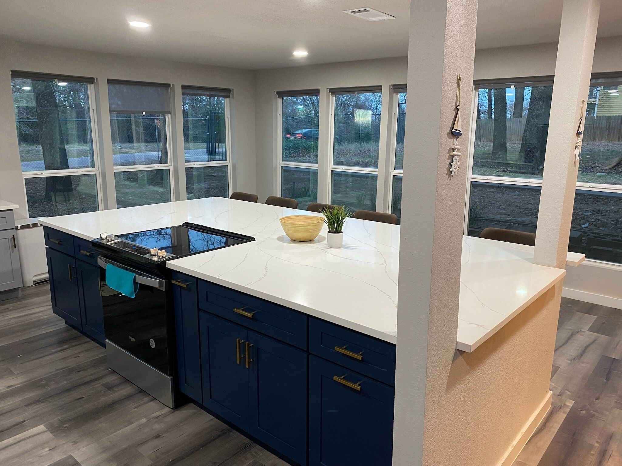 A modern kitchen with a large island, dark blue cabinets, and white countertops.