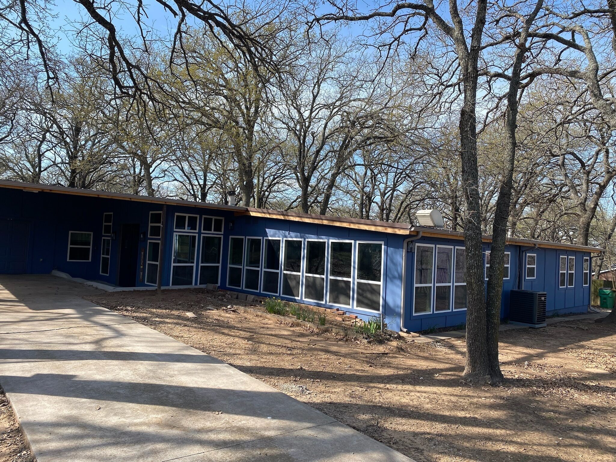 A blue single-story building with large windows, surrounded by trees.