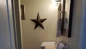 A narrow hallway leading to a bathroom with a star decoration on the wall, a sink, and a towel rack. - Sheepscot Harbour Studio #215 (Edgecomb)