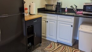 A compact kitchen with a black refrigerator, white cabinets, a microwave, and a toaster. - Sheepscot Harbour Studio #205 (Edgecomb)
