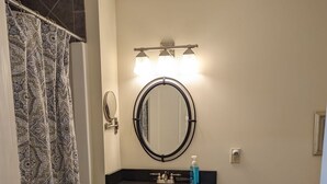 A bathroom with a vanity, a sink, a mirror, and a shower curtain. - Waterfront king studio with kitchen Sheepscot Harbour Studio #205 (Edgecomb)