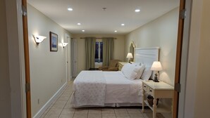 A hotel room with a bed, bedside tables, a lamp, a chair, and a window with curtains. - Sheepscot Harbour Studio #205 (Edgecomb)