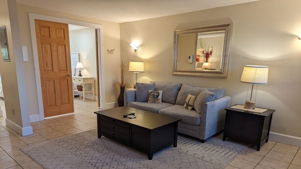 A living room with a sofa, coffee table, and two side tables. - Waterfront king studio with kitchen Sheepscot Harbour Studio #205 (Edgecomb)