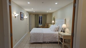 A hotel room with a double bed, bedside tables, a lamp, a chair, and a window with curtains. - Waterfront king studio with kitchen Sheepscot Harbour Studio #205 (Edgecomb)