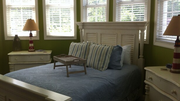 A bedroom with a bed, a nightstand, a dresser, and a window with blinds. - Sheepscot Harbour Studio #308 (Edgecomb)
