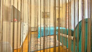 Una habitación con cama, escritorio y silla. Hay una ventana y una puerta.