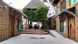 A courtyard with a thatched-roof gazebo, stone walls, and a tiled floor. - Tambo Marina Ecohostal - Hostel (Santa Catalina)