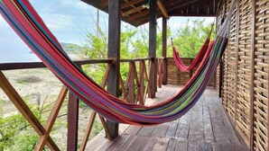 A wooden deck with a hammock and a view of greenery. - Tambo Marina Ecohostal - Hostel (Santa Catalina)