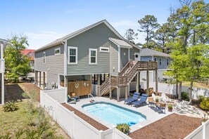 A two-story house with a backyard swimming pool, wooden deck, and outdoor seating area.
