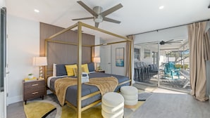 Ein modernes Schlafzimmer mit einem Himmelbett, Deckenventilator und Blick auf den Außenbereich.