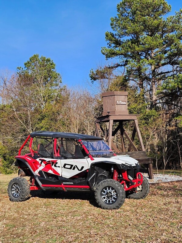 A red and white Honda ATV parked on a grassy area with trees in the background.