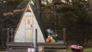 A wooden cabin with a porch, a rocking chair, and a small fire pit. - Two cozy pods with water tower (Kingston)