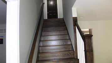 A wooden staircase with a dark finish, white handrails, and a closed door at the top.