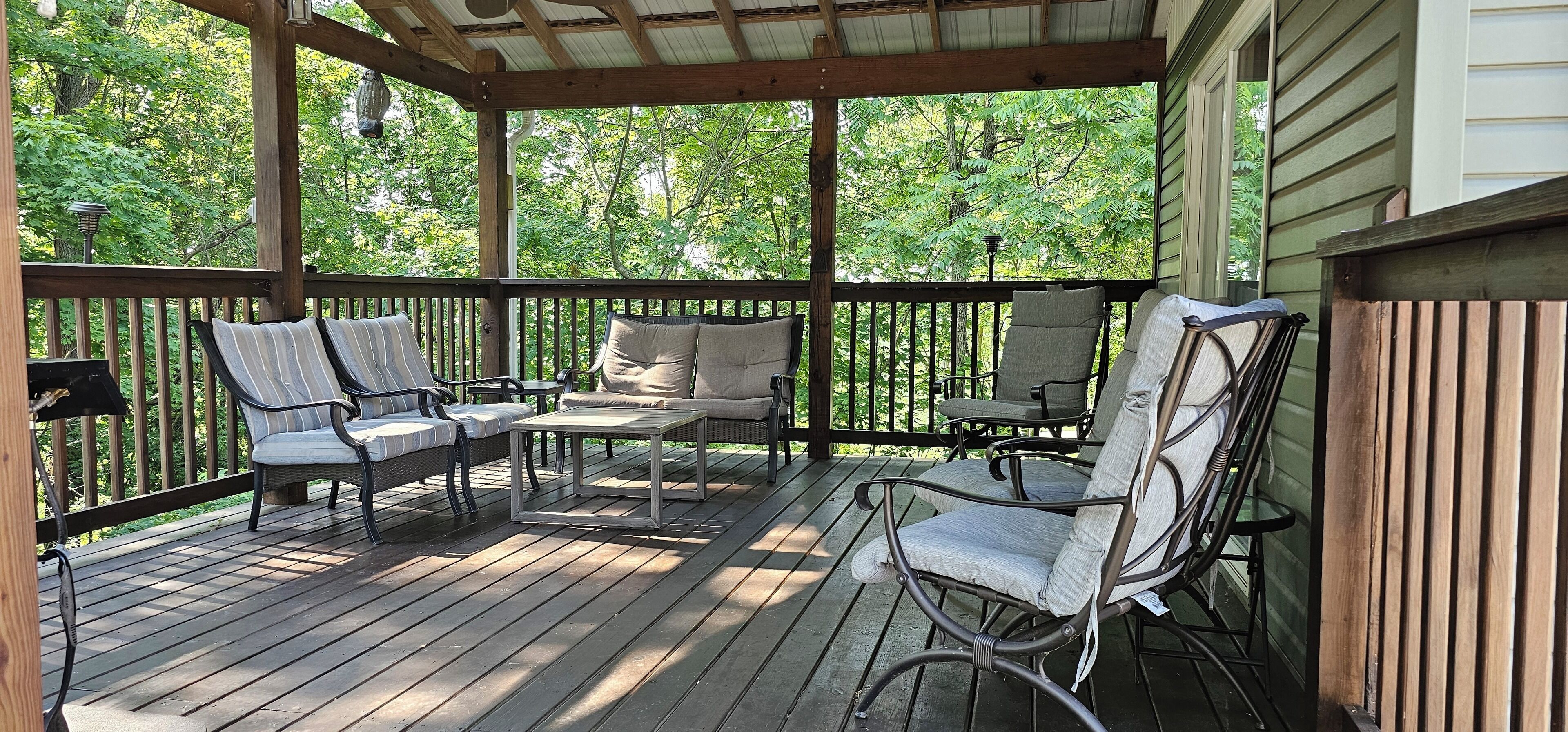 Une terrasse extérieure couverte, aménagée avec des meubles en osier et une table.
