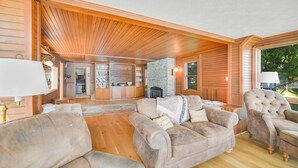A cozy living room with a fireplace, wooden ceiling, and a stone accent wall.