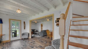 Amplia sala de estar con una escalera de madera, un comedor y vistas a través de un ventanal.
