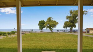 Un espacio al aire libre cubierto con césped, dos árboles y vista al mar.