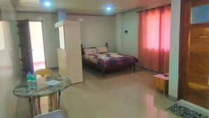 Habitación de hotel con cama, escritorio con silla, una mesita y un armario.