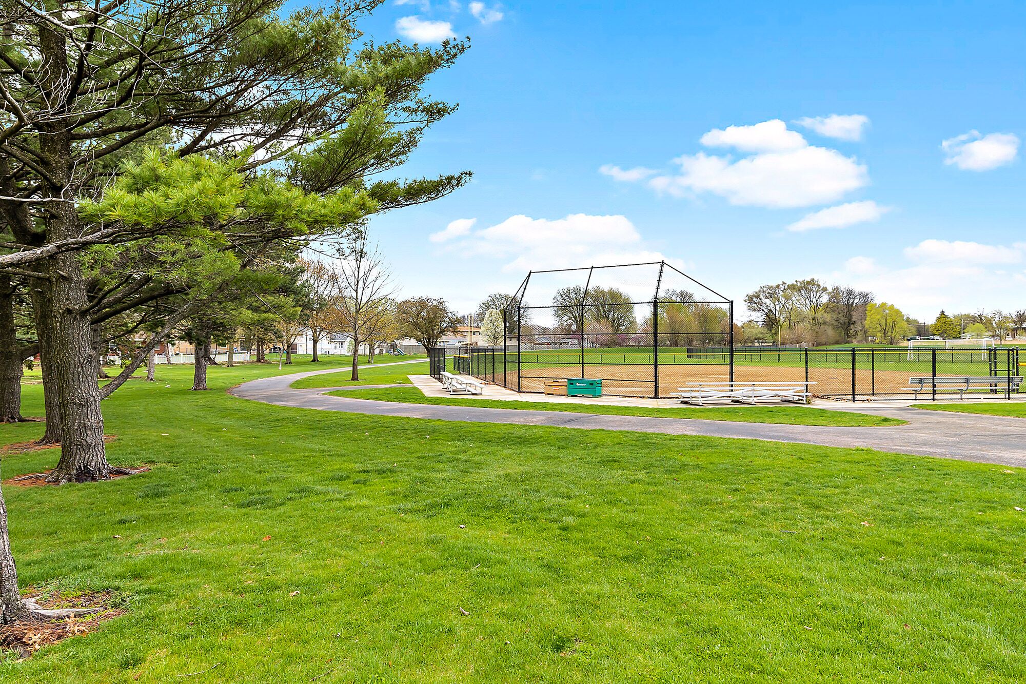 Un parc amb un camp de beisbol, bancs i un camí per passejar.