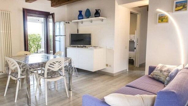 A modern living room with a dining area, a TV on a white cabinet, and a purple sofa. - S294 - Sirolo, wonderful three-room apartment with terrace and sea view (Sirolo)