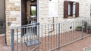 A stone building with a metal balcony railing, a door leading to an outdoor seating area, and a window with shutters. - S294 - Sirolo, wonderful three-room apartment with terrace and sea view (Sirolo)