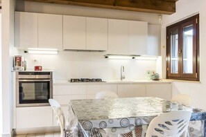 A kitchen with white cabinets, a stove, and a table with chairs.